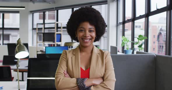 Portrait of mixed race businesswoman sitting looking at camera and smiling in office