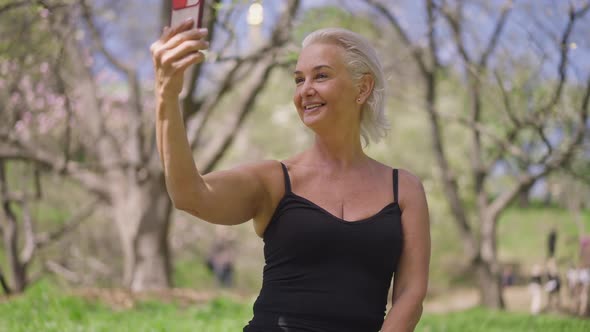 Happy Gorgeous Slim Senior Sportswoman Talking Smiling in Slow Motion Looking at Smartphone Screen