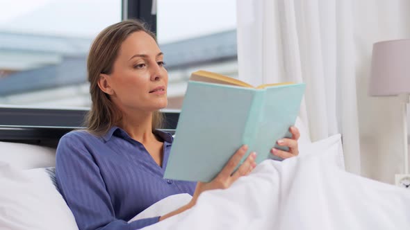 Woman Reading Book and Drinking Coffee in Bed