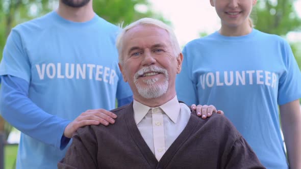 Smiling Volunteers Standing Behind Old Disabled Person, Social Support, Charity