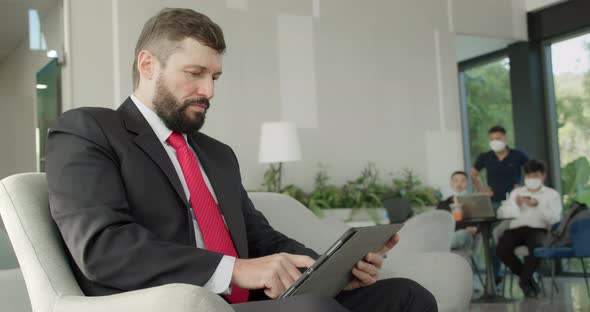 Serious Bearded Businessman Working on Laptop Computer in Office Lobby