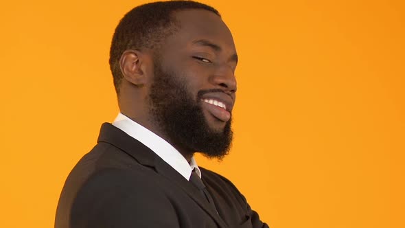 Funny African-American Man in Suit Making Faces and Dancing Against Background