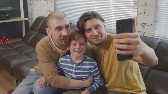 Cheerful Gay Fathers and Cute Child Taking Selfie