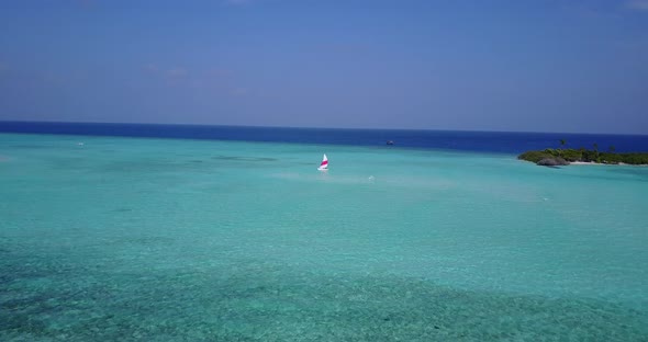 Natural flying travel shot of a white sand paradise beach and aqua turquoise water background in 4K