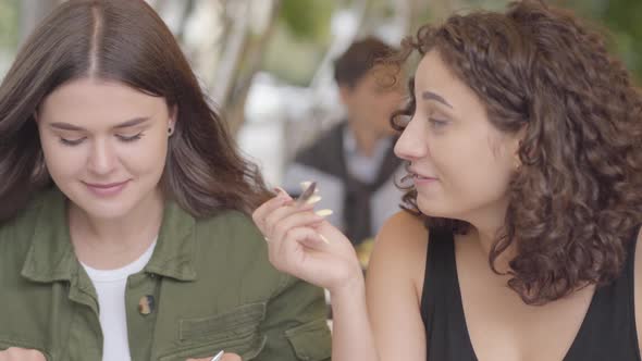 Portrait of Two Girlfriends Eating a Cake Sitting in Cafe Outdoors