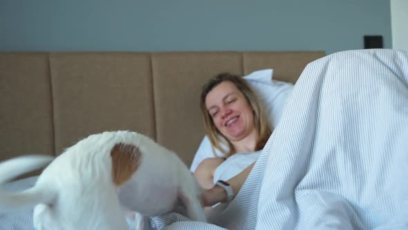 Woman Sleeping in Bed and Play with Her Dog