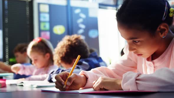 Attentive schoolgirl doing her homework in classroom