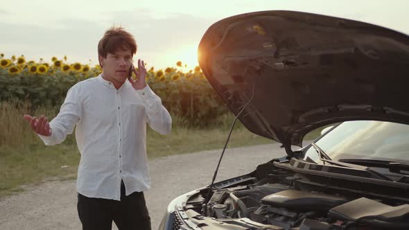 Man Stands Near His Car and Talks on the Phone