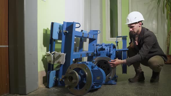 Technician in a Helmet Checks Technical Condition of New Elevator Equipment