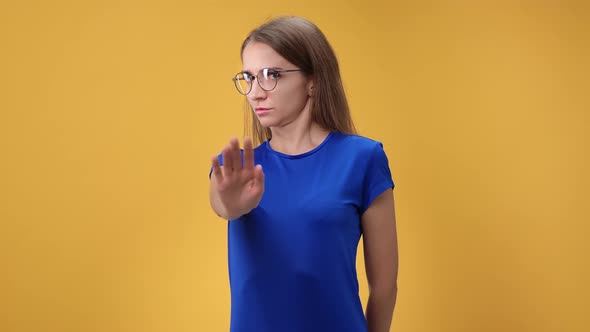 Confident Young Woman Shaking Head Frowning with No Gesture Posing Isolated on Orange Studio