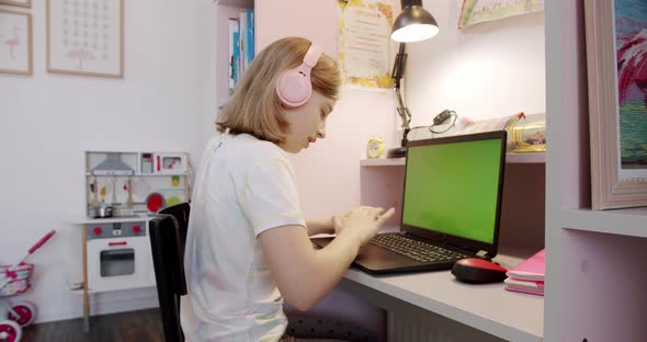 Teenage Girl is Using Laptop at Home Video Online Lesson on Green Screen