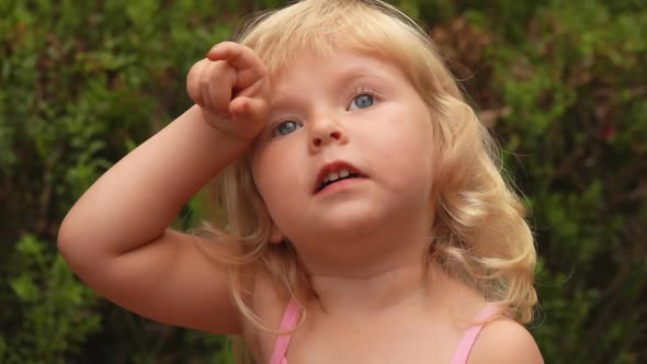 Little Blond Girl Is Looking Up at the Sky and Showing Something with Her Finger