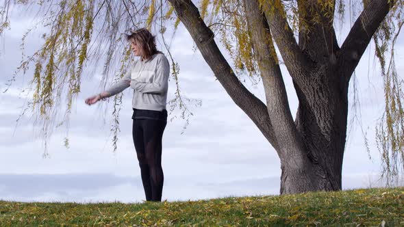 Woman jogging and stopping under tree for quick break