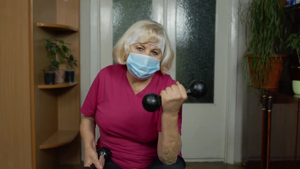 Elderly Senior Grandmother Making Weight Lifting Dumbbells Exercising During Coronavirus Lockdown