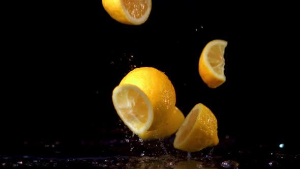 Super Slow Motion Pieces of Fresh Lemon Fall on the Table with Splashes of Water