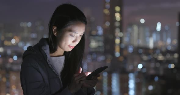 Woman use of cellphone over city background at night