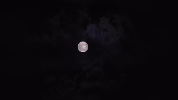 Bright Full Moon Behind Fast Moving Dark Clouds on Night Sky