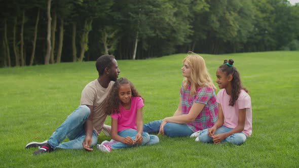 Diverse Family with Daughters Relaxing on Green Lawn