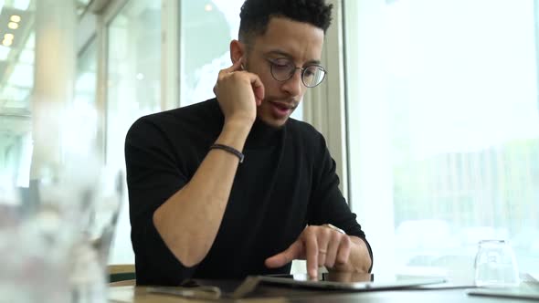 Businessman talking on the phone using wireless earphones and digital tablet