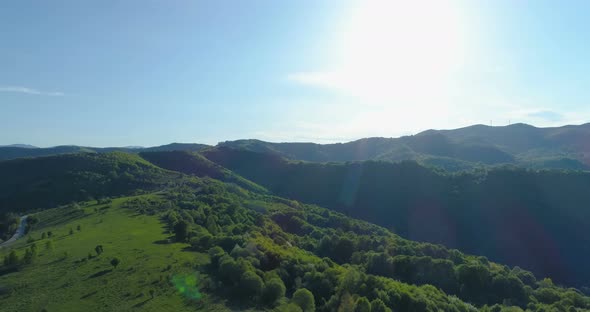 Aerial Shot of Woods, Green Hills and Meadows Under Bright Shining Sun and Blue Sky