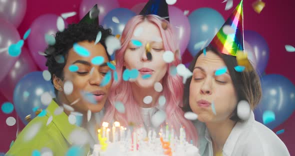 Three Friendly Millennial Women Blowing Candles on Birthday Cake Party with Confetti Rain