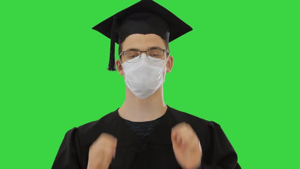 Young Man with Graduation Gown in Medical Mask on a Green Screen, Chroma Key