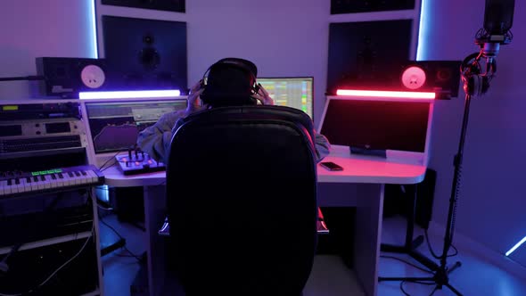 Soundwoman in Cap and Headphones Working in the Recording Studio with Computer and Mixer Creating