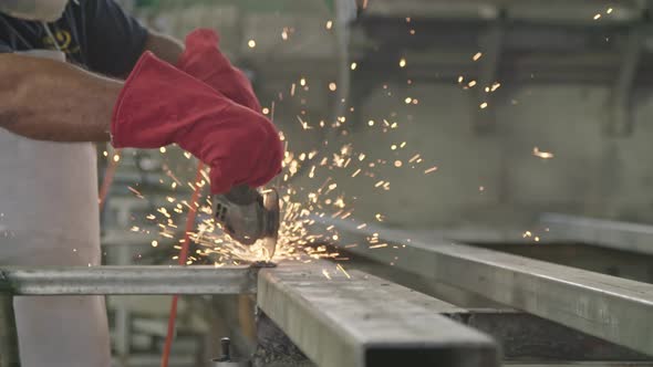 Slow motion of a worker using metal grinder with sparks flying at a metal shop