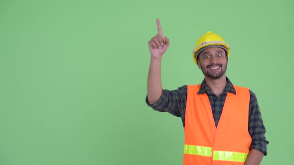 Happy Young Bearded Persian Man Construction Worker Pointing Up