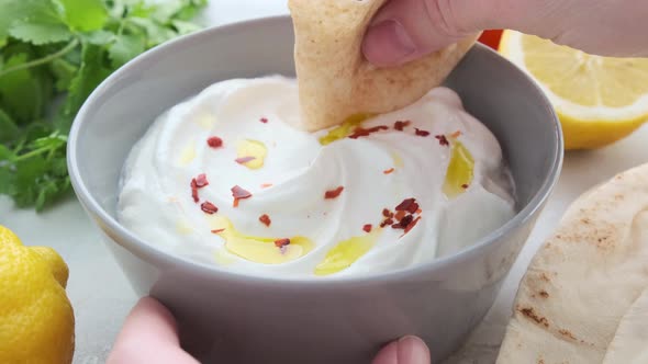 Whipped feta cheese dip with garlic and lemon in gray bowl.