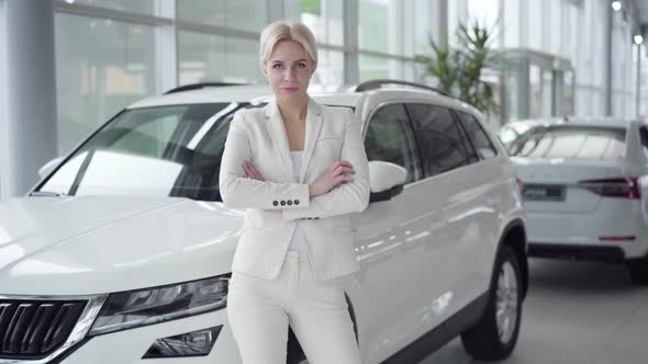 Young Successful Businesswoman in Elegant Suit Posing in Car Dealership