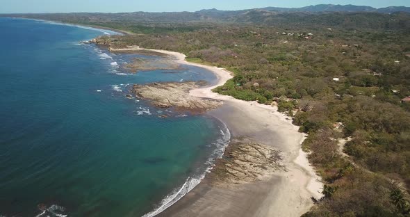 Aerial drone view of the beach, rocks and tide pools in Playa Palada, Guiones, Nosara, Costa Rica.