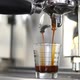 Black coffee being brewed by the machine flowing through portafilter into espresso shot glass - VideoHive Item for Sale