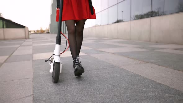 Young Woman Walks with Electric Scooter