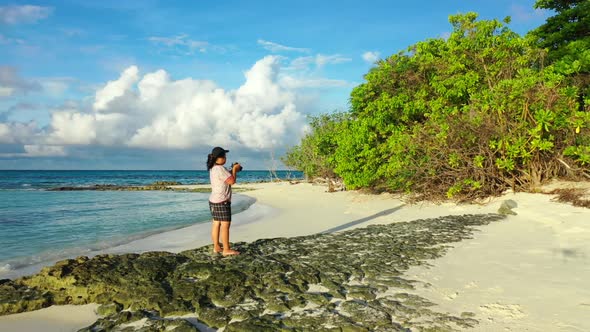 Female model sunbathing on marine coastline beach wildlife by blue ocean and white sandy background 