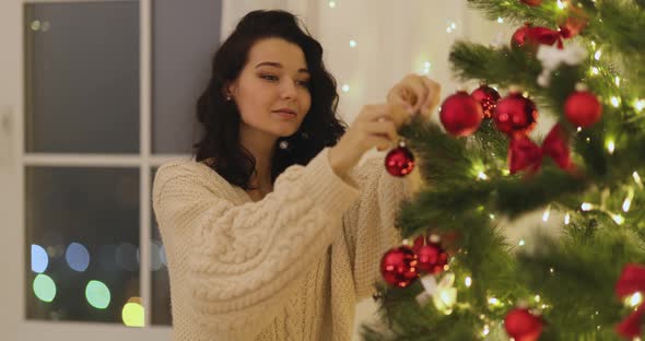 Woman Decorating Christmas Tree with Christmas Tree Toys at Home