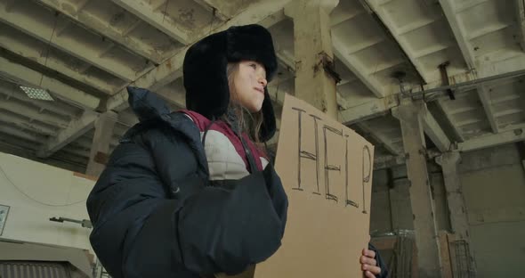 Homeless Caucasian Girl in Dirty Clothes Standing with the Help Cardboard and Asking for Help