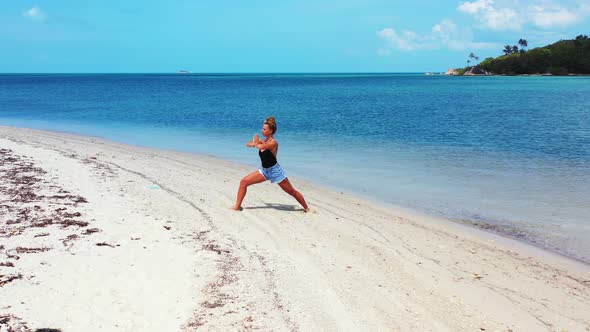 Pretty fun women on photoshoot enjoying life on the beach on clean white sand and blue 4K background