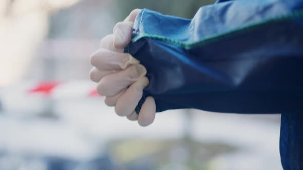 Female Caucasian Hands Putting on White Gloves with Red and White Warning Tape at Background in