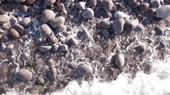 Winter Aerial Flight Top Over Waves Rolling on Artic Ocean Shore with Round Stones Ocean Waves at