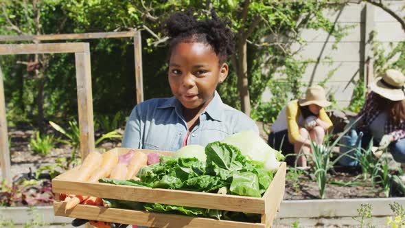 Portrait of happy african american girl gardening, looking at camera and smiling