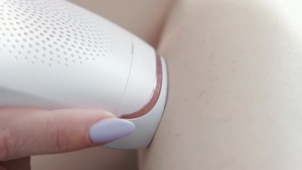 Woman doing hair removal with laser epilator. Cosmetic procedures at home. Laser hair removal