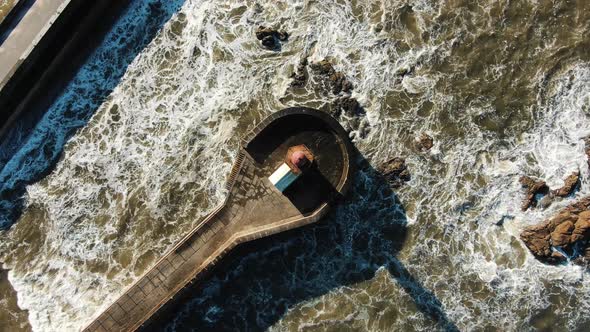 Flycam Rises Vertically Above Old Lighthouse Among Ocean