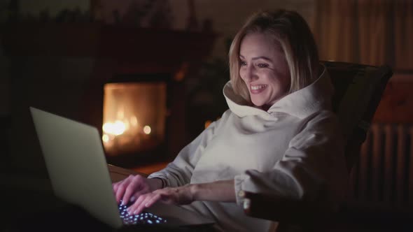 European Woman Working on a Laptop Near a Fireplace