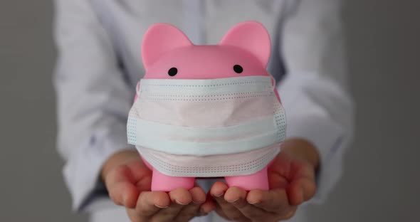 Businesswoman holding piggybank with medical mask