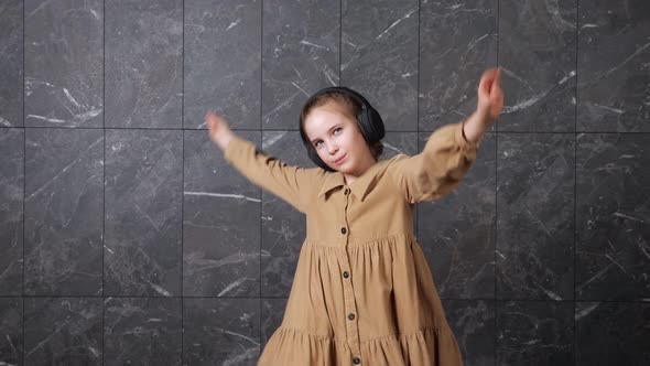 Excited Schoolgirl Listens to Music in Black Headphones