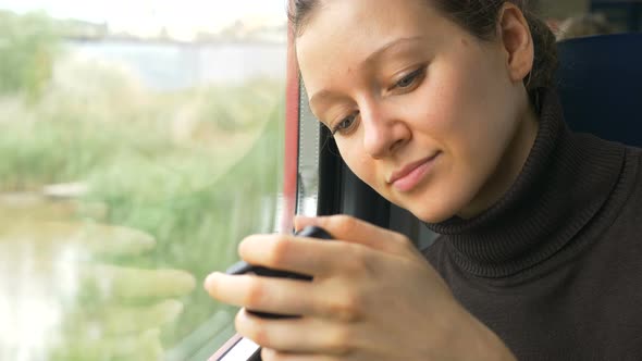 Pretty Young Woman Looks at Modern Smartphone Display