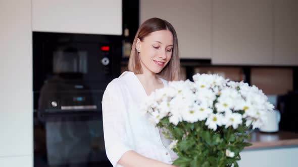 Beautiful Woman Putting Fresh White Flowers Into a Vase