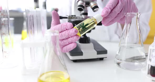 Scientist in Gloves Holds Bottle of Marijuana Oil in Laboratory