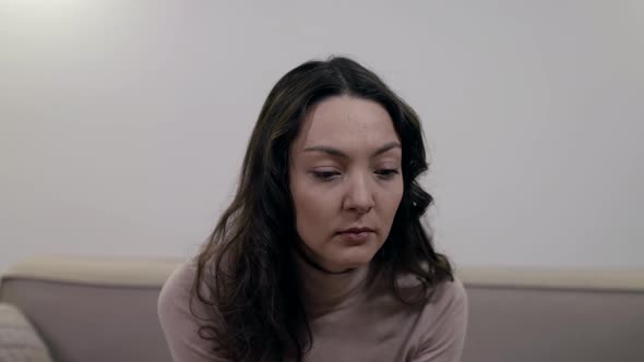 Depressive Thoughtful Woman Is Sitting Alone at Room and Thinking Leaning on Hand By Chin